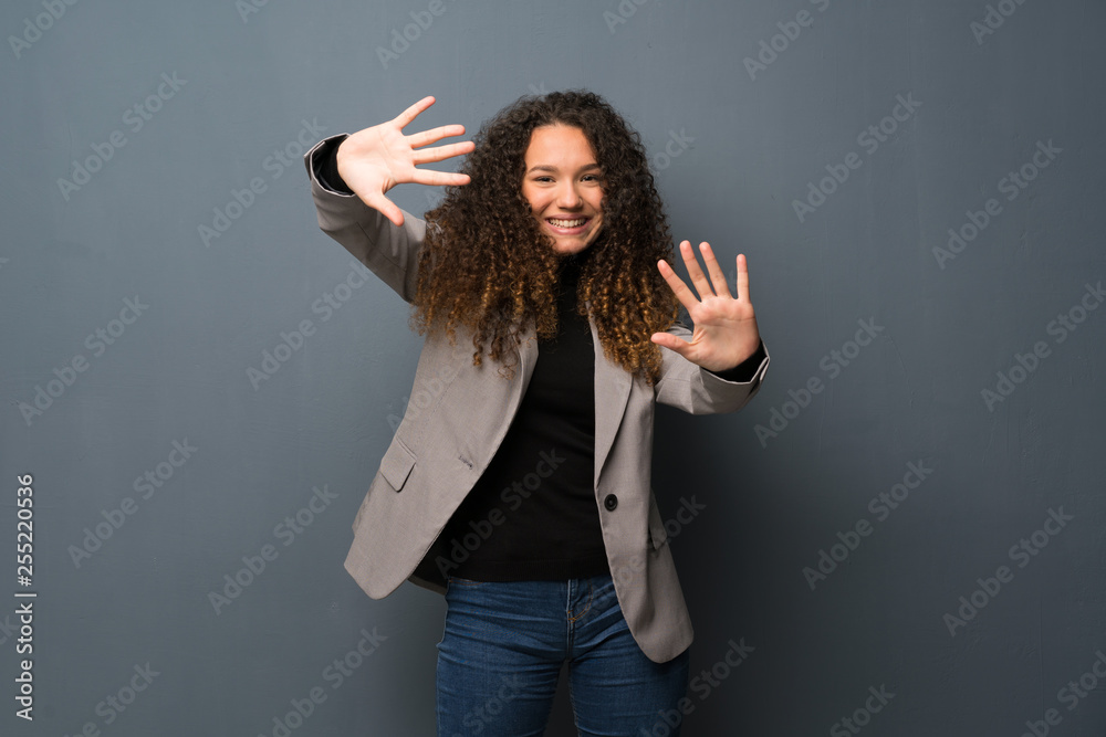 Teenager girl over blue wall counting ten with fingers Teenager girl over blue wall counting ten with fingers