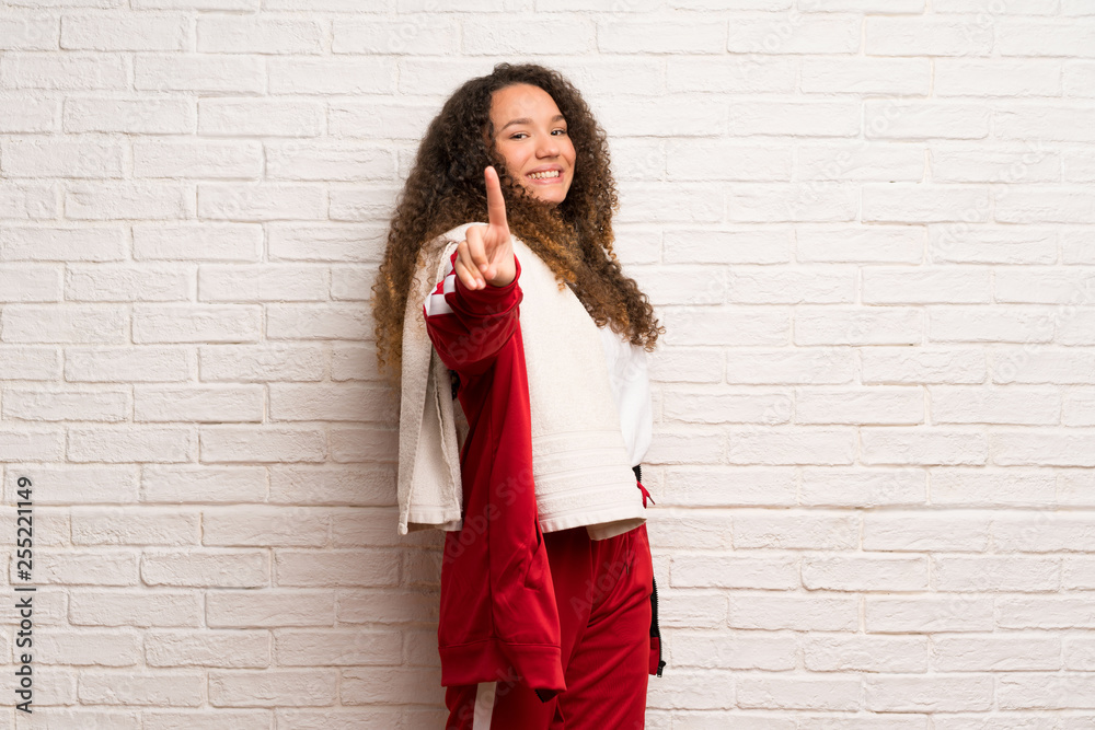 Teenager sport girl with curly hair showing and lifting a finger Teenager sport girl with curly hair showing and lifting a finger