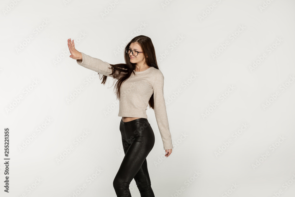 Side view photo of joyful happy european girl with long brunette hair wearing black leggings and glasses Side view photo of joyful happy european girl with long brunette hair wearing black leggings and glasses