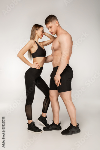 Attractive young sporty couple, shirtless man and beautiful woman in black sportswear