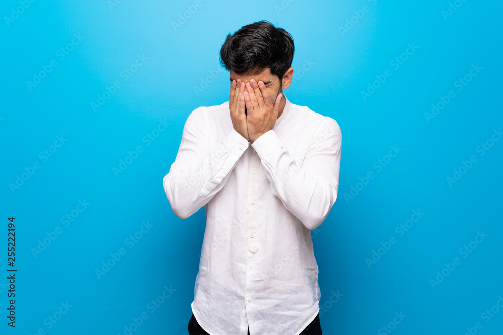 Young man over isolated blue wall with tired and sick expression
