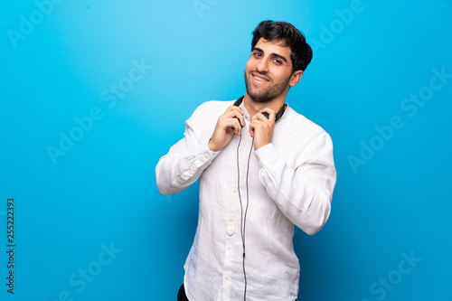 Young man over isolated blue wall with headphones