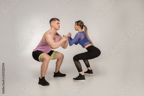Young attractive couple in trendy sportswear doing sguats together