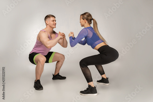 Attractive fitness coach shows the beautiful girl how to do sguats