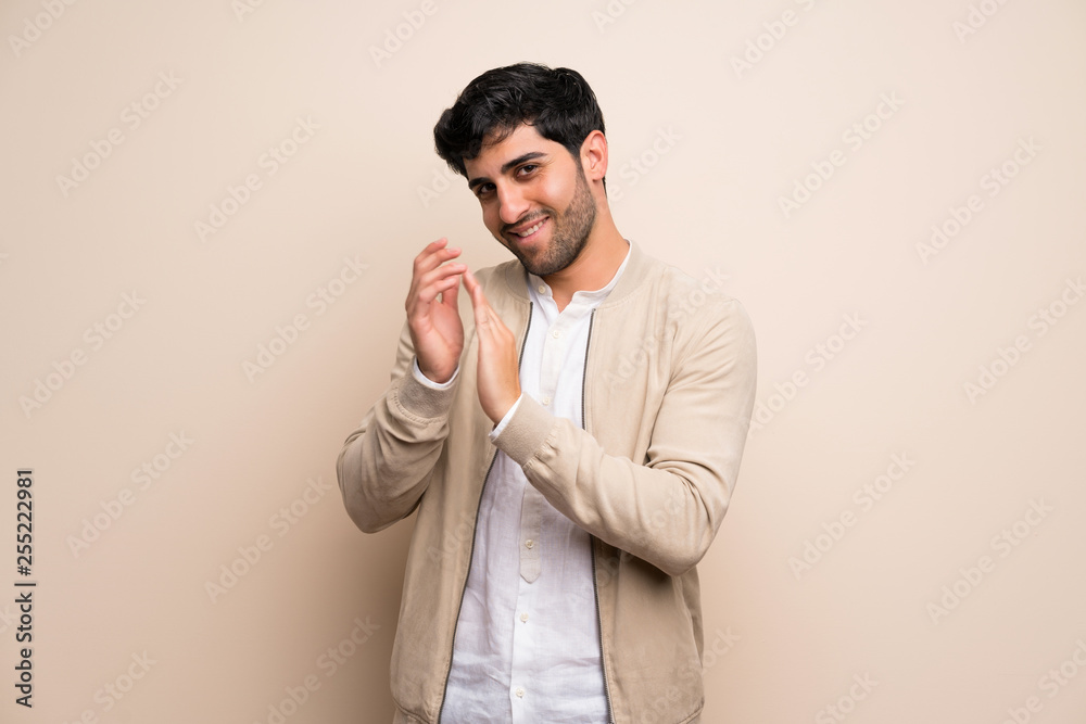 Young man over isolated wall applauding after presentation in a conference Young man over isolated wall applauding after presentation in a conference