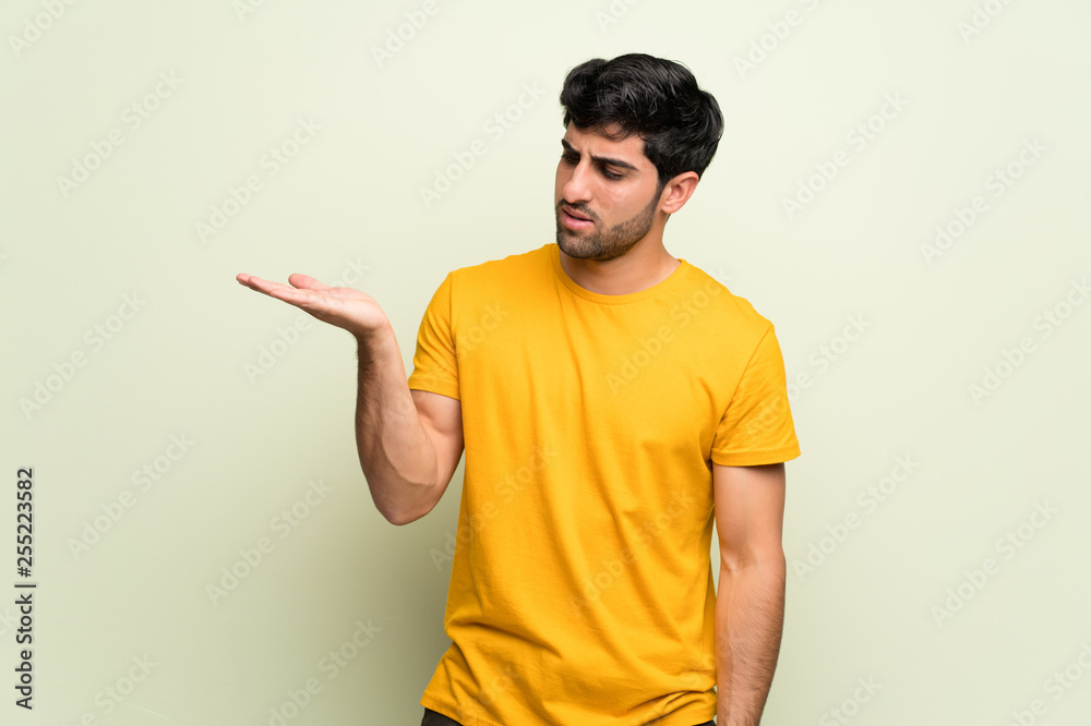Young man over pink wall serious while holding copyspace imaginary Young man over pink wall serious while holding copyspace imaginary