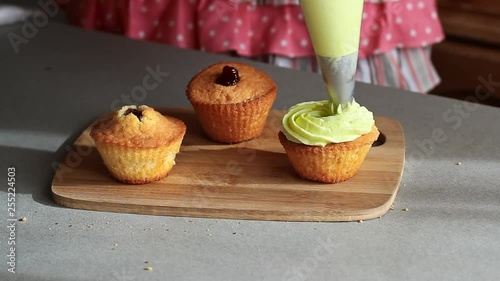 Young confectioner decorates cupcakes with lemon cream and grape close up photo