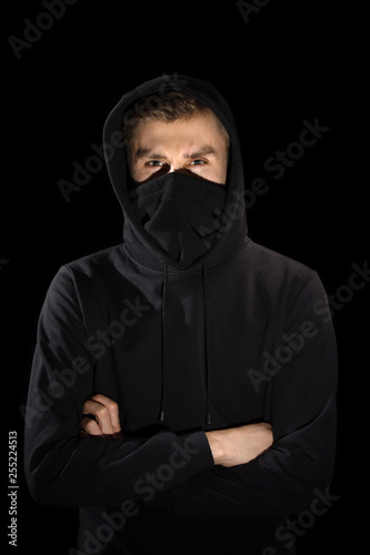 faceless man with open eyes in hoodie standing isolated on black