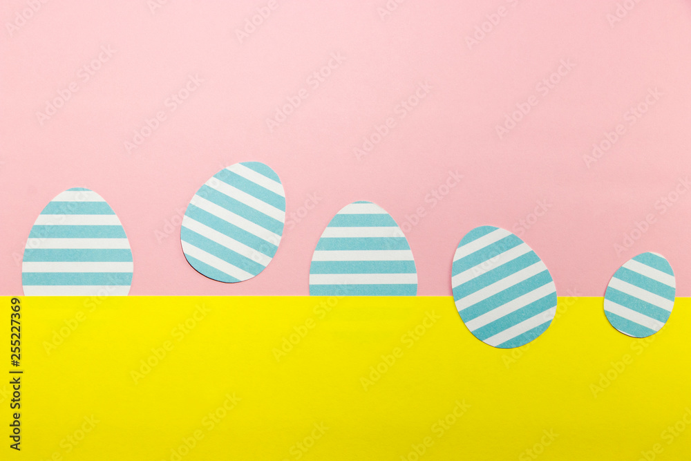 Blue striped easter eggs on a yellow and pink background. Easter festive background. Postcard.