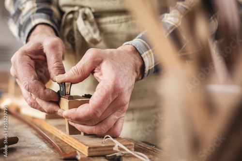 Hände eines Instrumentenbauers bei der Arbeit mit dem Geigenbogen