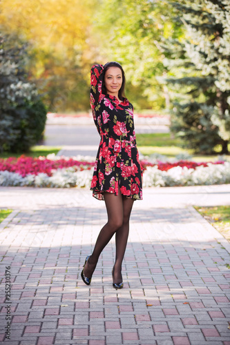 Happy young fashion woman in floral dress in city park © Wrangler