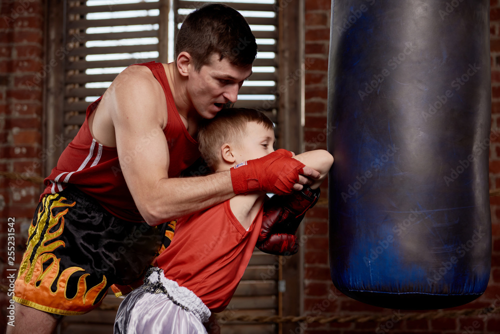 Child strikes with the hands on training gloves coach instructor. Boxing training with a coach inside the Boxing ring.