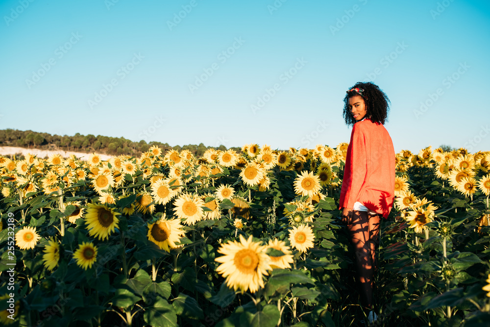 Happy young black woman walking in a sunflower field Happy young black woman walking in a sunflower field