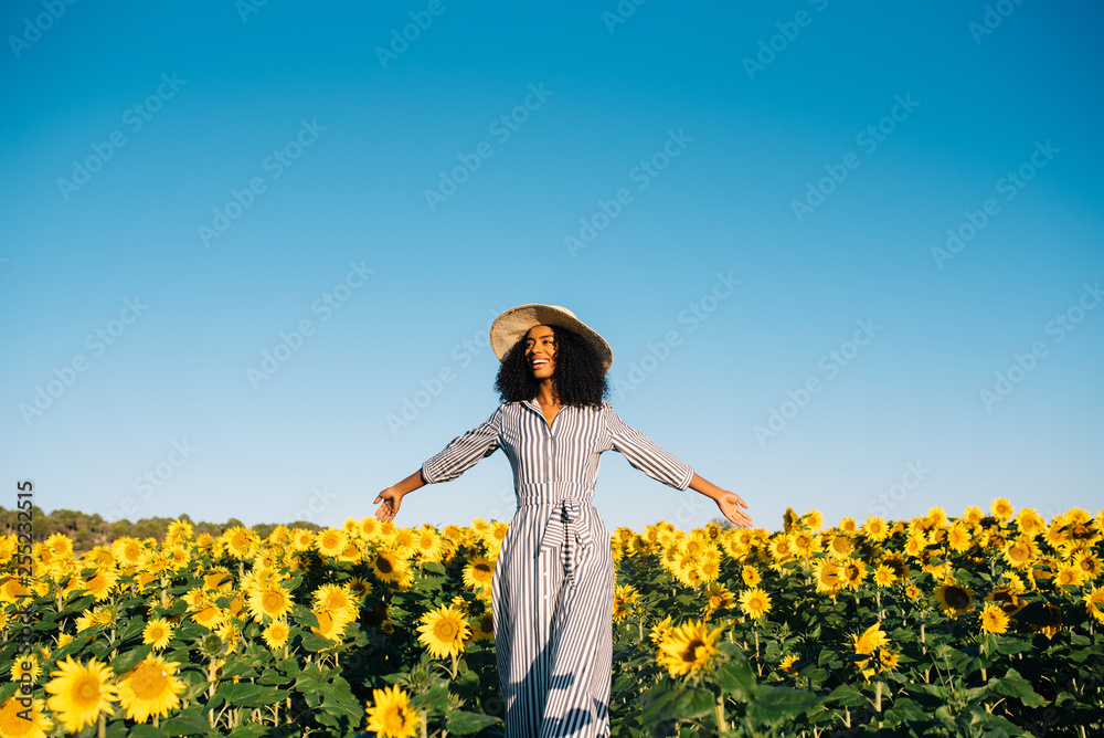 Happy young black woman walking in a sunflower field Happy young black woman walking in a sunflower field