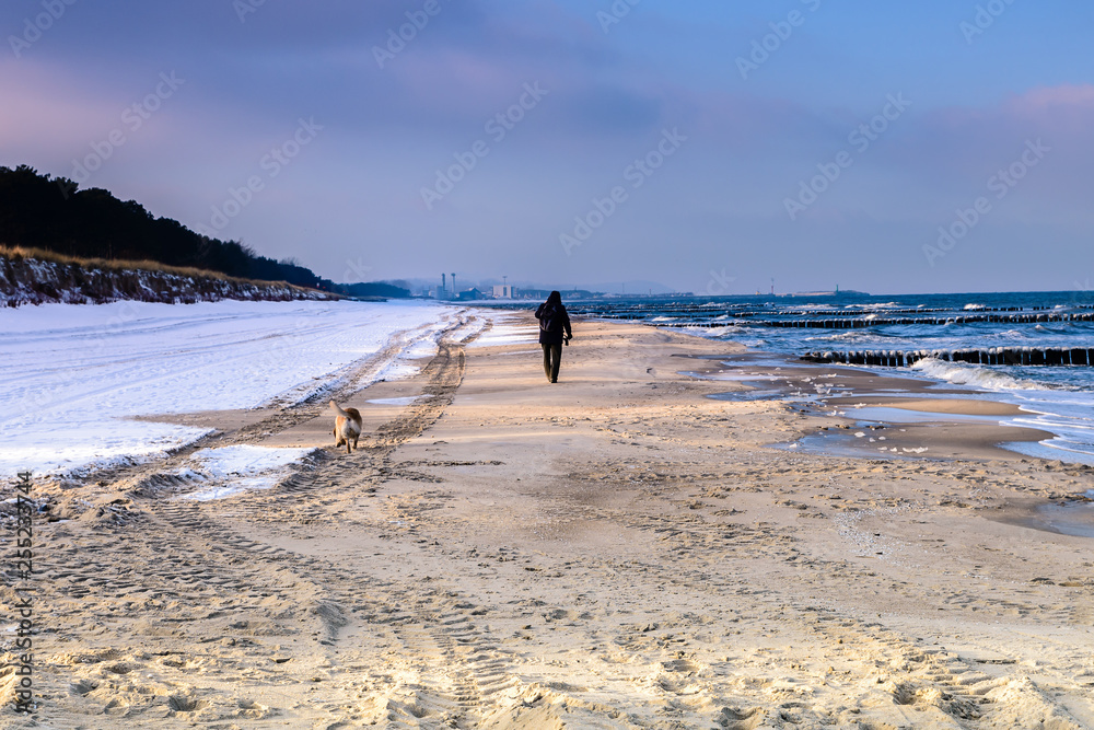 Hel Peninsula (Poland) in wintertime. Sundy beach in dusk with people walking along water