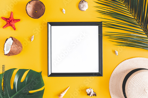 Summer composition. Tropical palm leaves  photo frame  coconut  hat on yellow background. Summer  nature concept. Flat lay  top view  copy space
