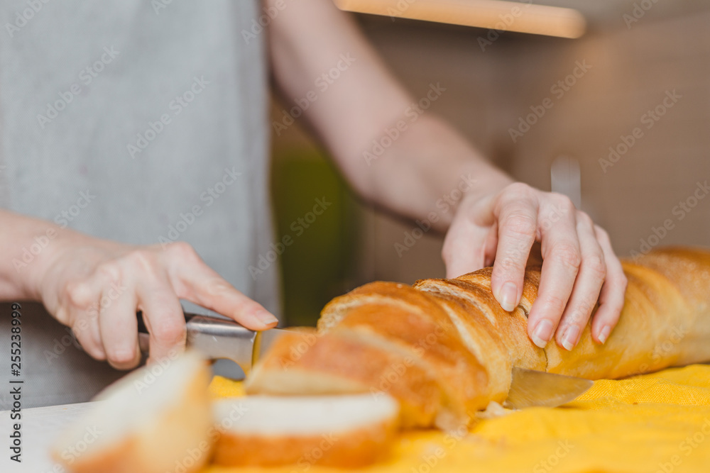 Fresh baked baguette bread on wooden cutting board - making sandwiches