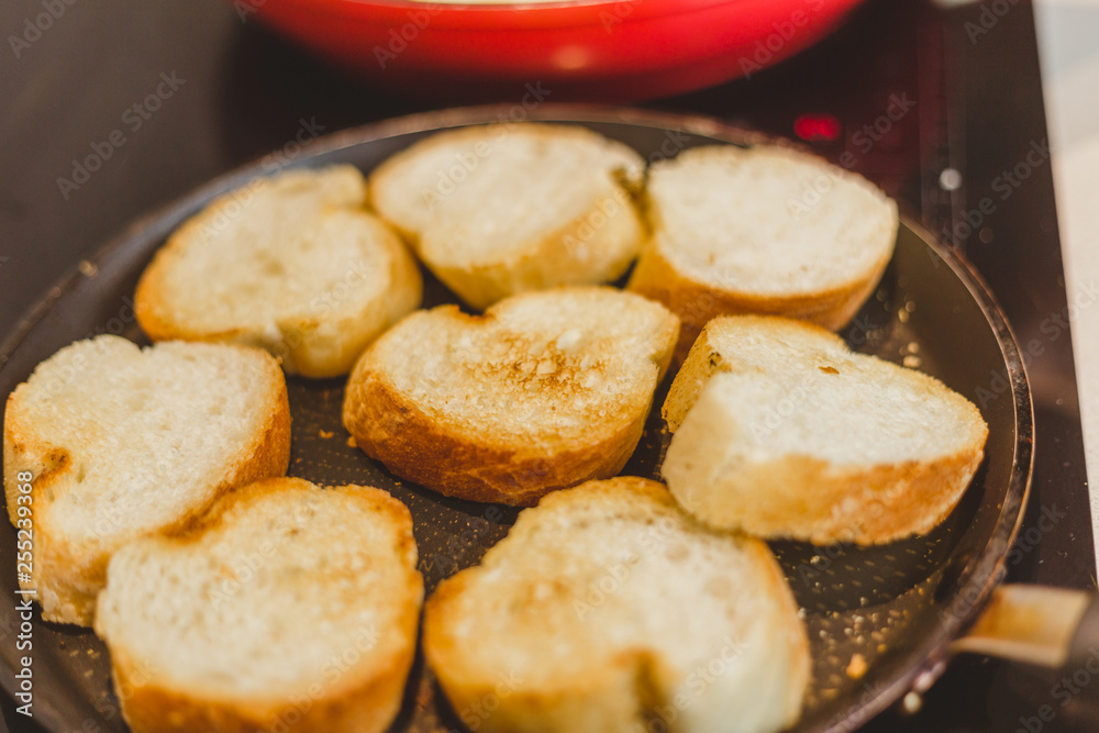Closeup of housewife frying baguette pieces in a frying pan - making cold snacks - tapas and sandwiches Closeup of housewife frying baguette pieces in a frying pan - making cold snacks - tapas and sandwiches