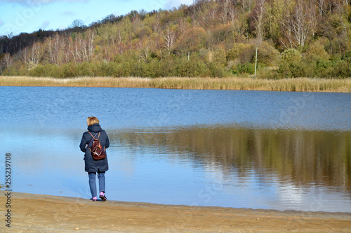 The woman with a backpack costs on the bank of a lagoon of the Baltic Sea. Settlement Amber, Kaliningrad region