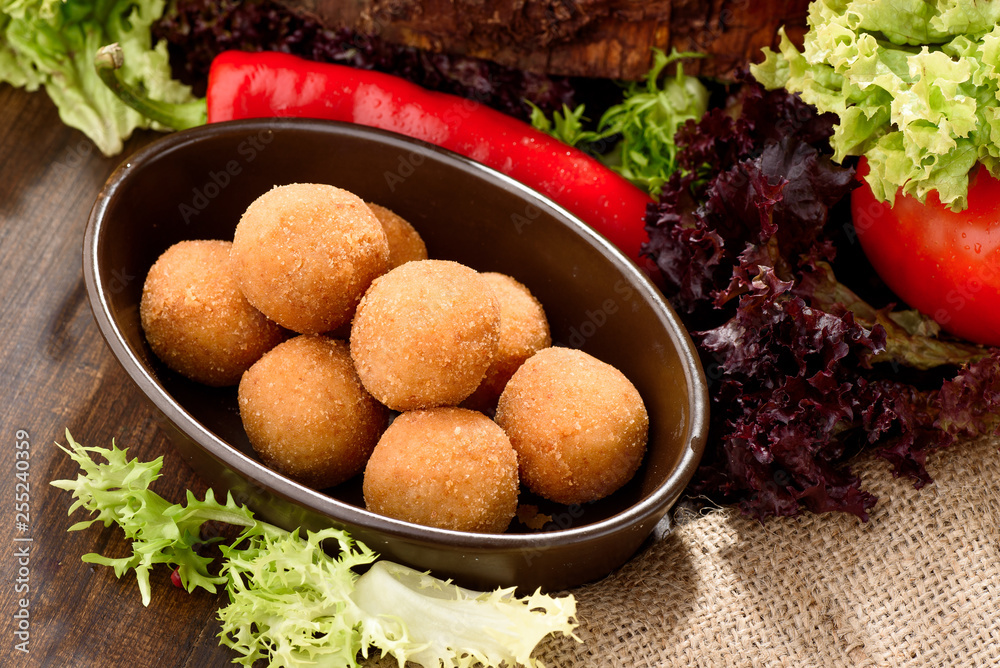 Cheese balls on a white plate close up among lettuce leaves on a wooden background. Beer Snack. Close-up. Space Cheese balls on a white plate close up among lettuce leaves on a wooden background. Beer Snack. Close-up. Space