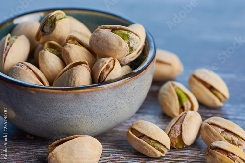 close up color picture of pistachios roasted and salted in a ceramic bowl on a wooden surface