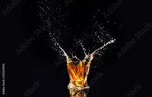 whiskey with splash on black background, brandy in a glass