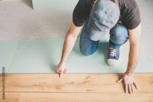 The builder is engaged in laying laminate in the room - repair and finishing work