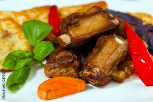 barbecued pork ribs with fried potato pancakes, served with basil, grilled carrots and paprika, restaurant menu photo photo