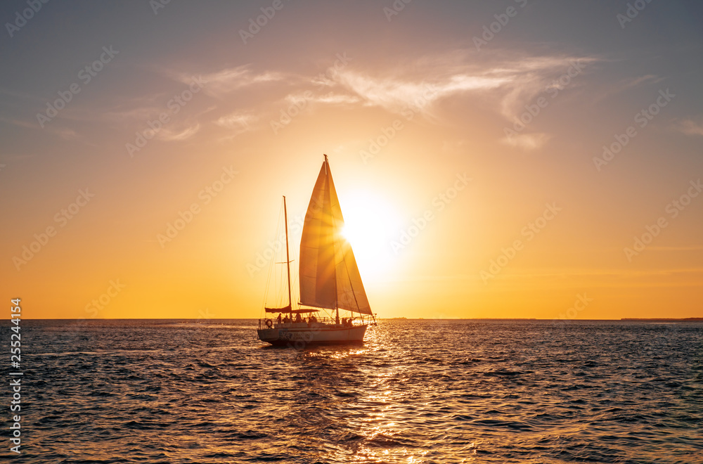Sailing yacht in the ocean at sunset - obrazy, fototapety, plakaty 
