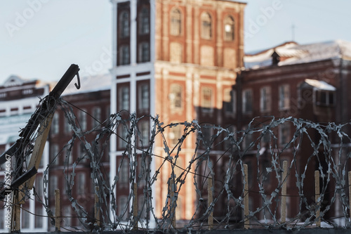 The old prison brick building protected by barbed wire