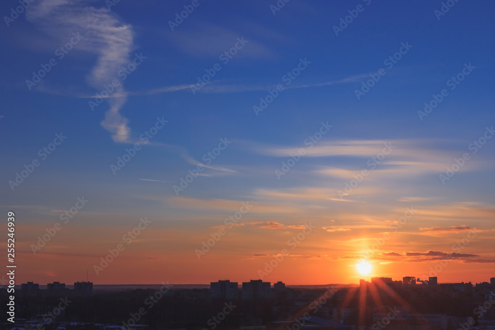 A cityscape of buildings under sunset with colorful cloudy sky