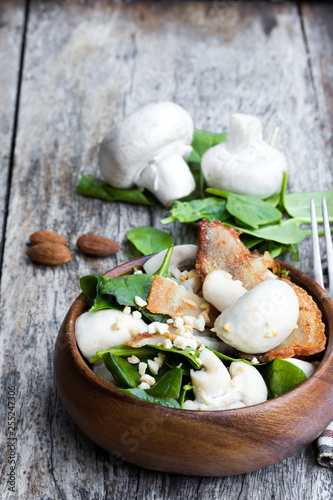 Healthy mushroom salad with spinach and bacon on wooden table