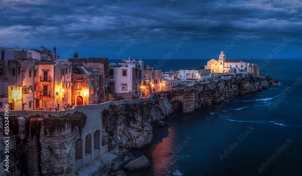 Small town during cloudy evening on southern coast of Italy. Amazing and atmospheric view, street lamps creation special look. Town on a cliff washed by sea. Beautiful popular travel destinatination.