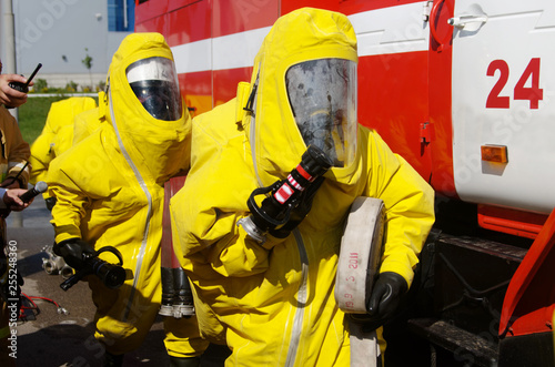 Two firefighters in protective suits and gas masks are preparing for work photo