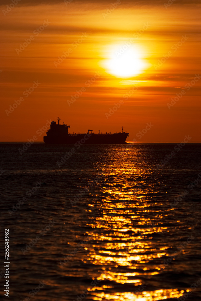 Freighter Ship At Sunset in the Puget Sound. As the sun sets over the horizon a freighter sails north in the Salish Sea area of western Washington state.