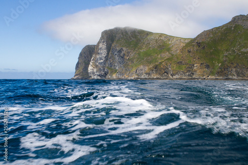 Steilküste der norwegischen Insel Runde bei leicht bewölktem Himmel