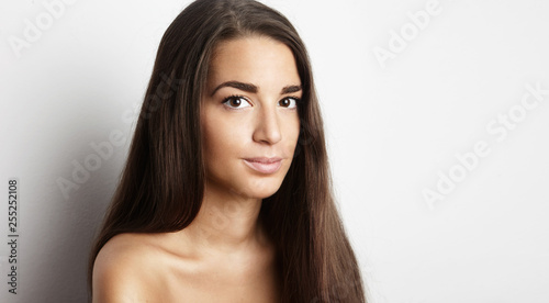 Portrait of handsome pretty young female with long hair at empty white background wall. Space for copy paste text message