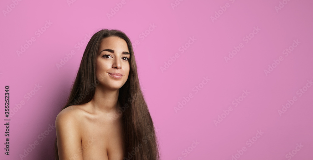Portrait of beautiful young happy smiling woman with long curly hair, over pink background.Space for copy paste text message Portrait of beautiful young happy smiling woman with long curly hair, over pink background.Space for copy paste text message