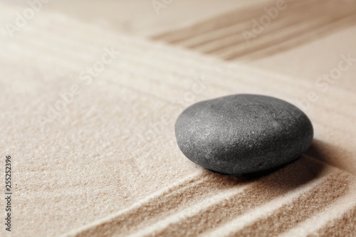 Zen garden stone on sand with pattern, space for text. Meditation and harmony