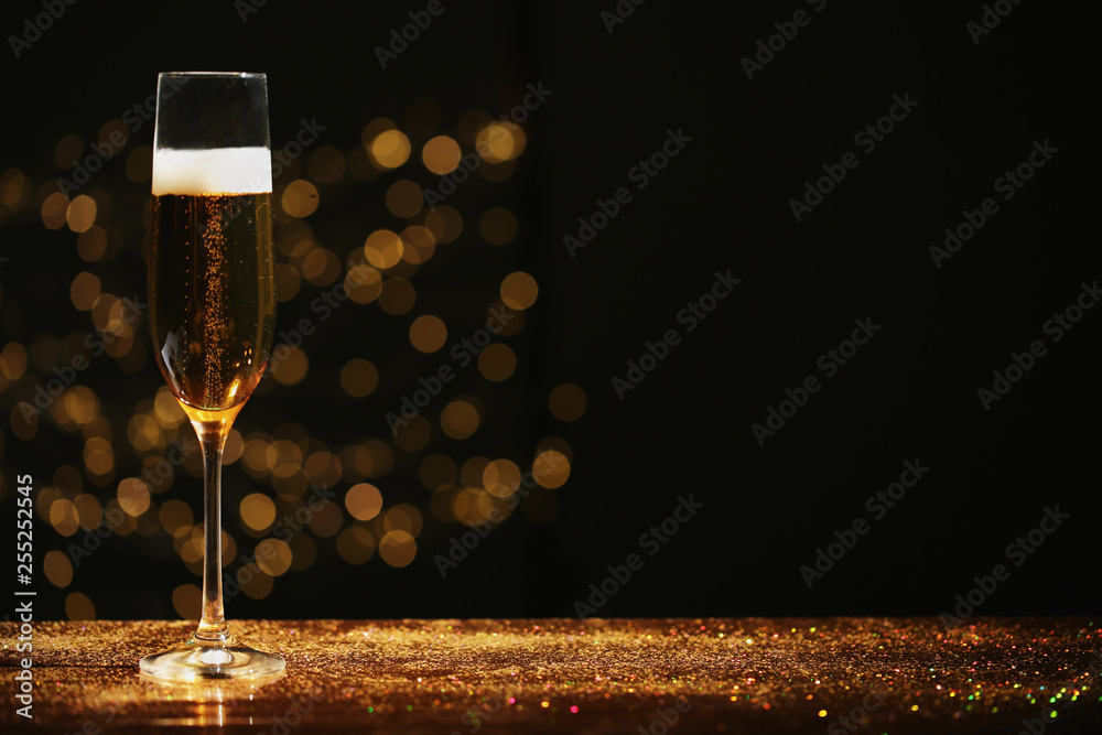 Glass of champagne and golden glitter on table against blurred background.  Space for text Stock Photo | Adobe Stock