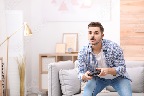 Fototapeta Naklejka Na Ścianę i Meble -  Emotional young man playing video games at home