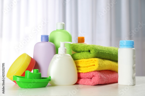 Baby cosmetic products, toy and towels on table indoors