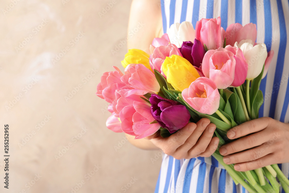 Girl holding bouquet of beautiful spring tulips on color background, closeup with space for text. International Women's Day