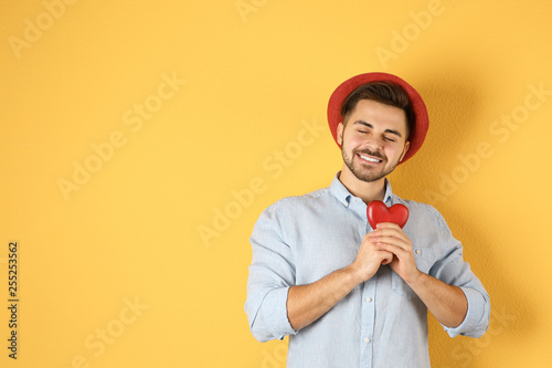 Man holding decorative heart on color background, space for text