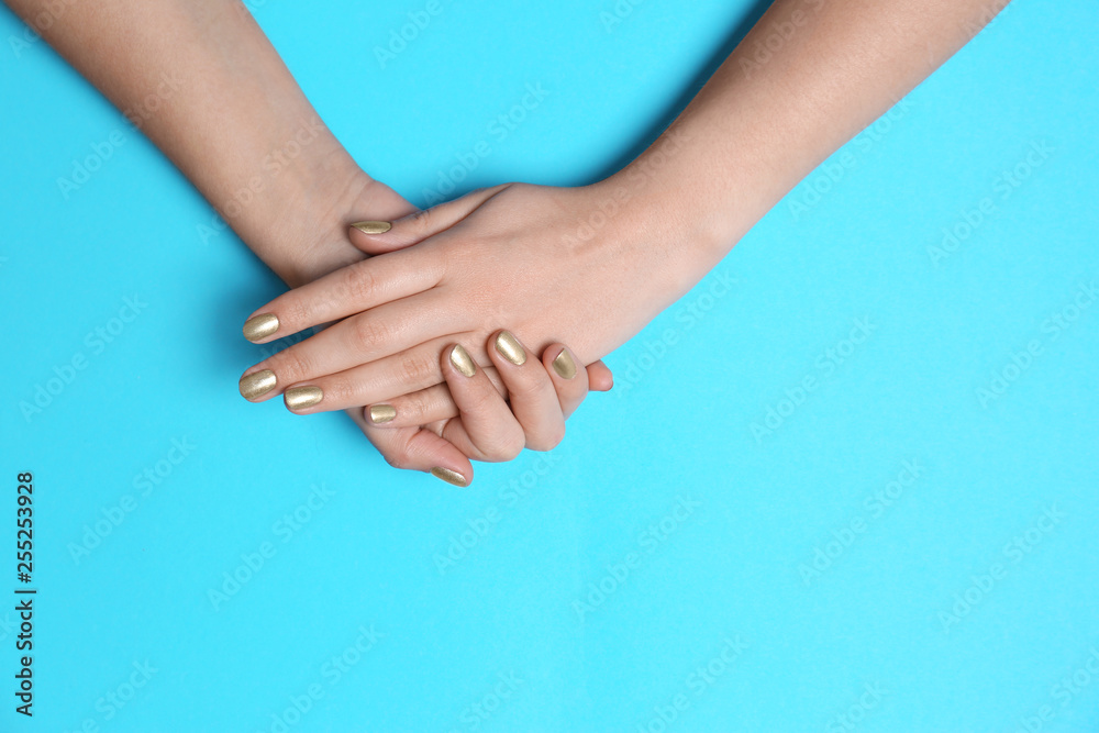 Woman showing golden manicure on color background, top view with space for text. Nail polish trends