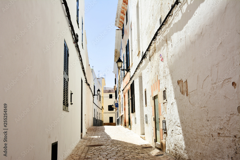 narrow street with white houses in mahon, spain