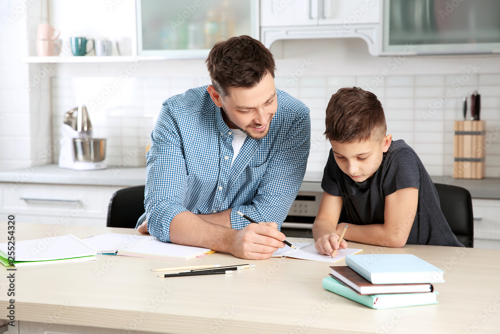 Dad helping his son with homework in kitchen Dad helping his son with homework in kitchen