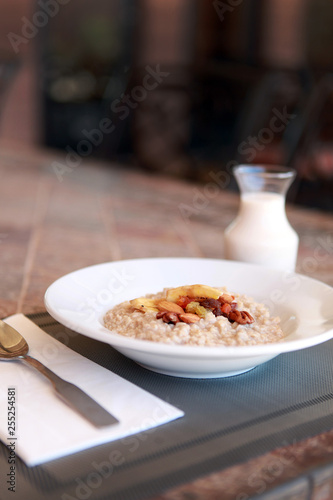 Close up bowl of breakfast oatmeal with dried fruit and milk