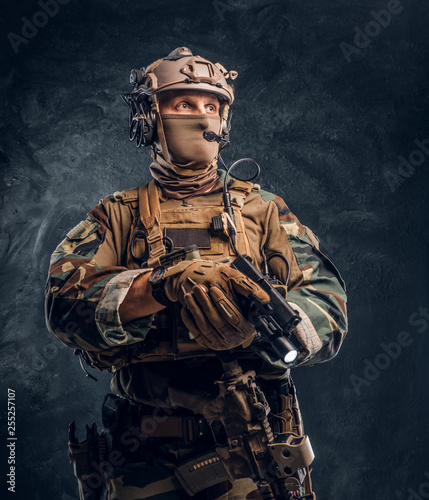 Obraz na plátně Elite unit, special forces soldier in camouflage uniform holding a gun with a flashlight and looking sideways