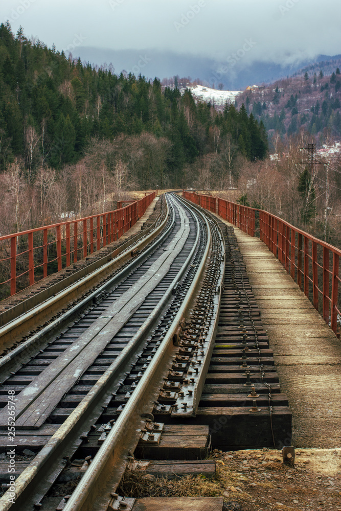 empty railway railroad tracks with old vintage wooden ties sleepers leads from viewer to mountains. way path concept. outdoor spring image